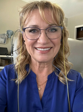 Dr. Lisé Spurlock-DeLong, wearing neurofeedback sensors, smiling at the camera.